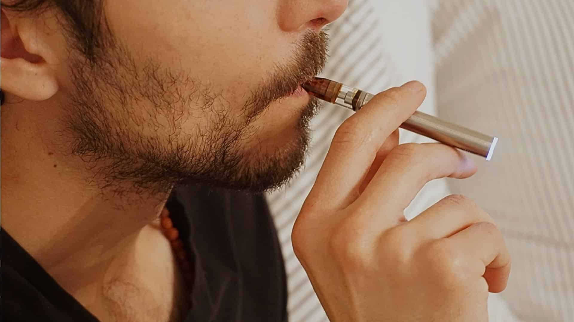 A close-up shot of a man smoking a vape (e-cigarette).